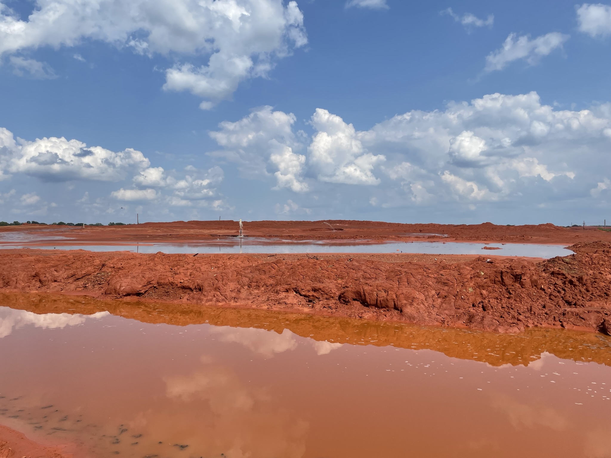 red mud and water reflecting blue sky above