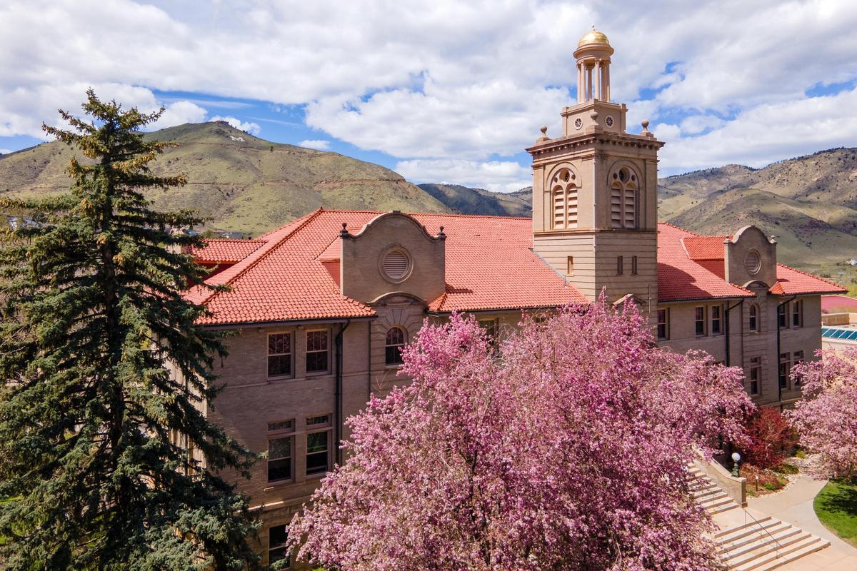Guggenheim Hall with flowering pink trees, Mount Zion and blue sky with clouds