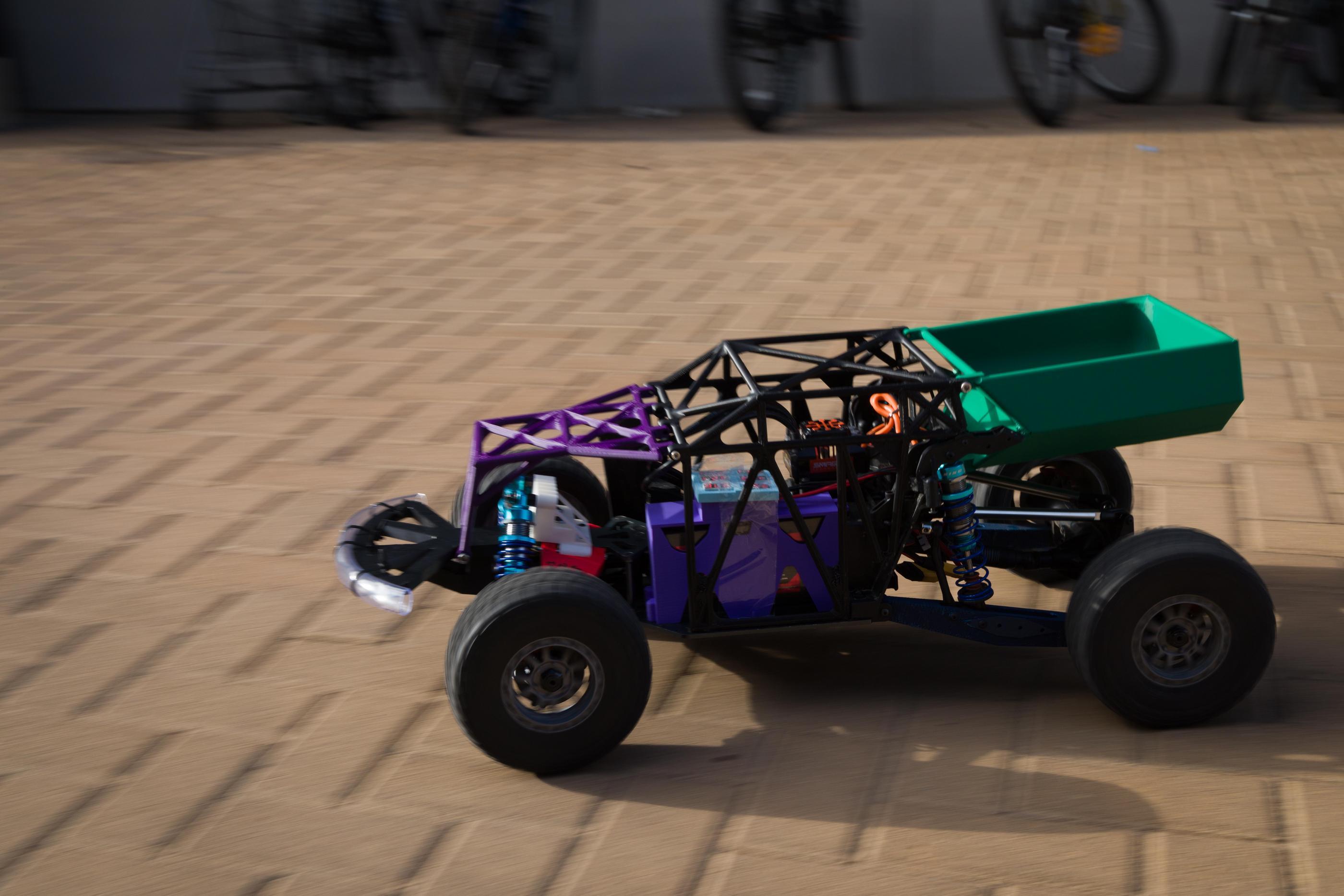 a multicolored rc car driving on a brick surface