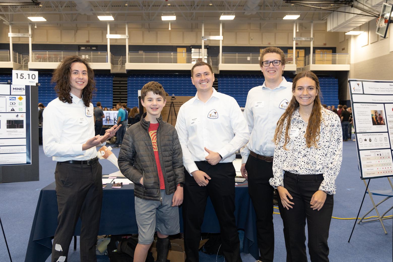 Members of the E-Stim for Oliver team pose with Oliver, the 12-year-old who they designed a device for, at the Spring 2023 Capstone Design Showcase.