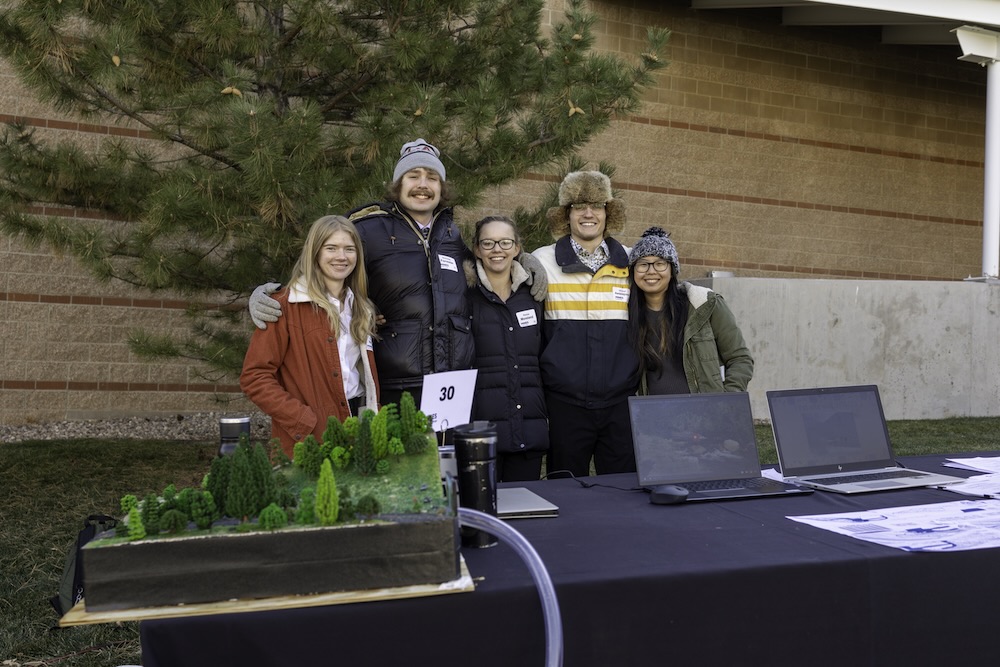 Students who placed third in the 2023 Senior Capstone Design project at Colorado School of Mines stand in front of their display table..