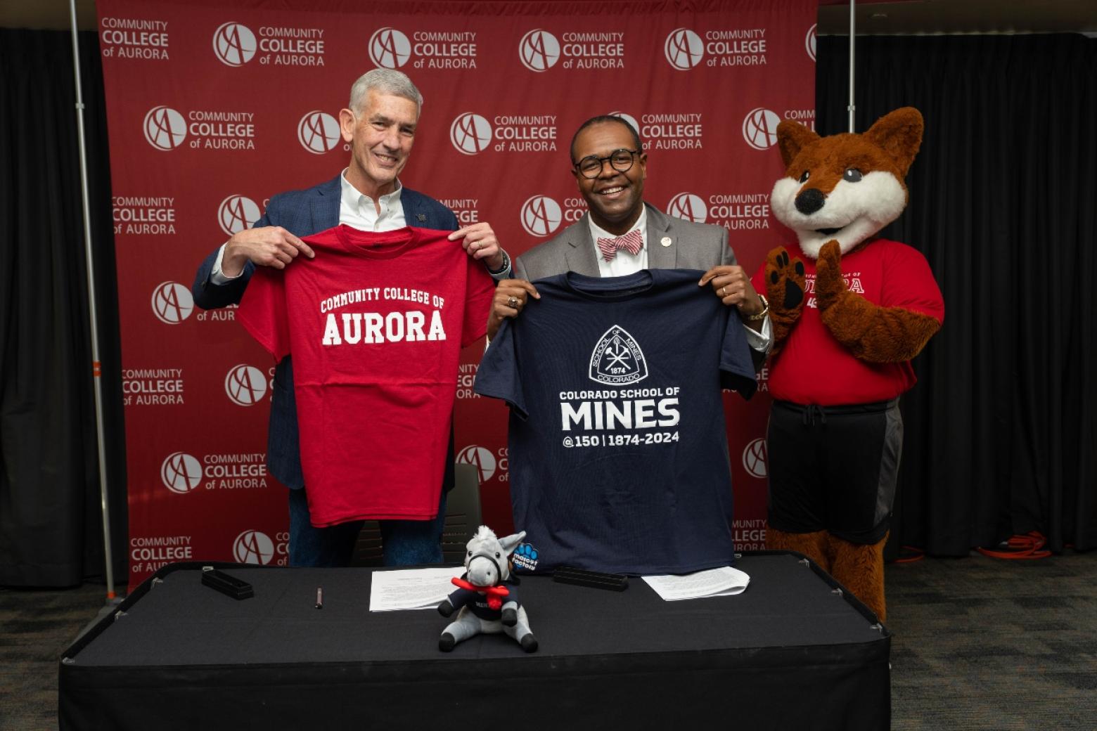 Mines President and CCA president pose with t-shirts from respective schools