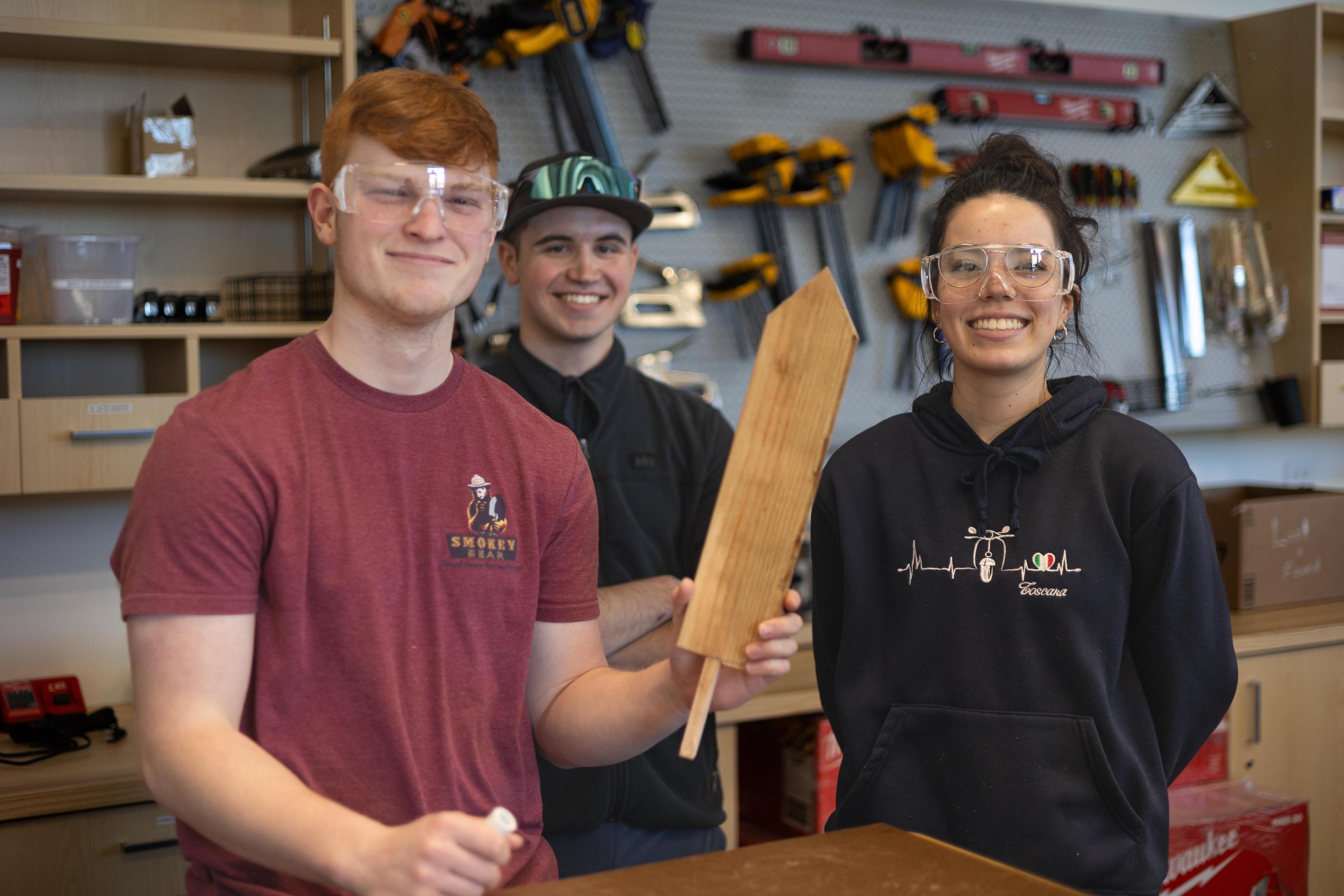 Three students pose with a wooden prototype in the Labriola Innovation Hub