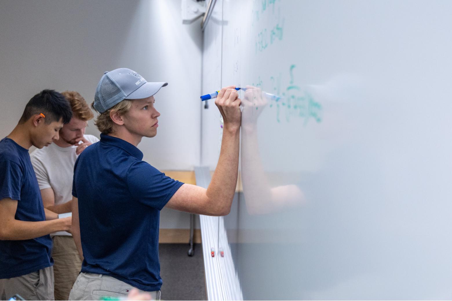 Mines students work problems on the whiteboard in an Electrical Engineering course.
