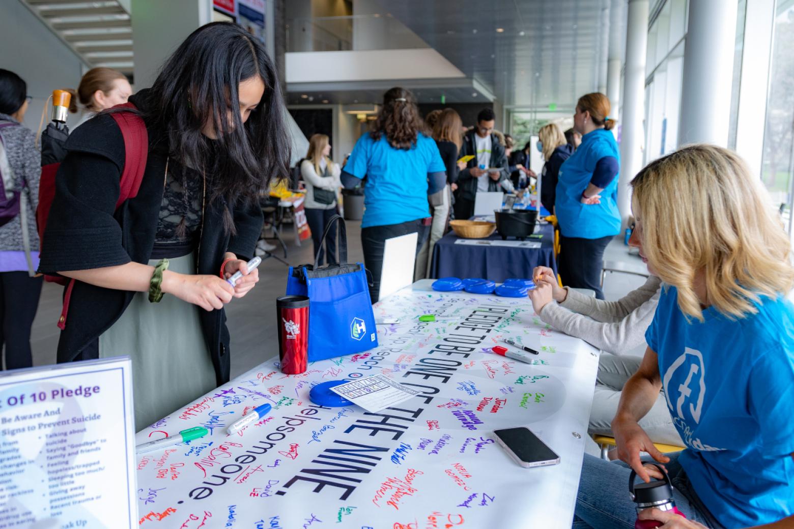 A Mines student signs a banner with the Nine Out of Ten suicide prevention pledge at Fresh Check Day 2022