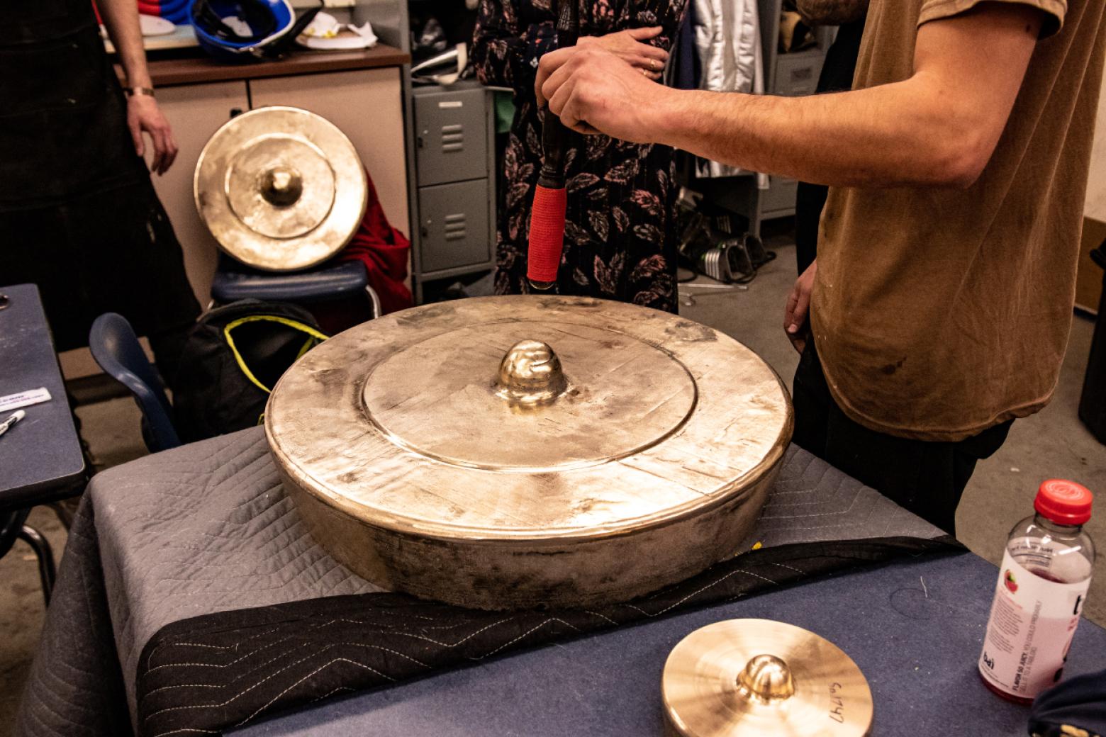 Volunteers help tune one of the cymbals cast from a custom bell metal alloy created with recycled cymbals