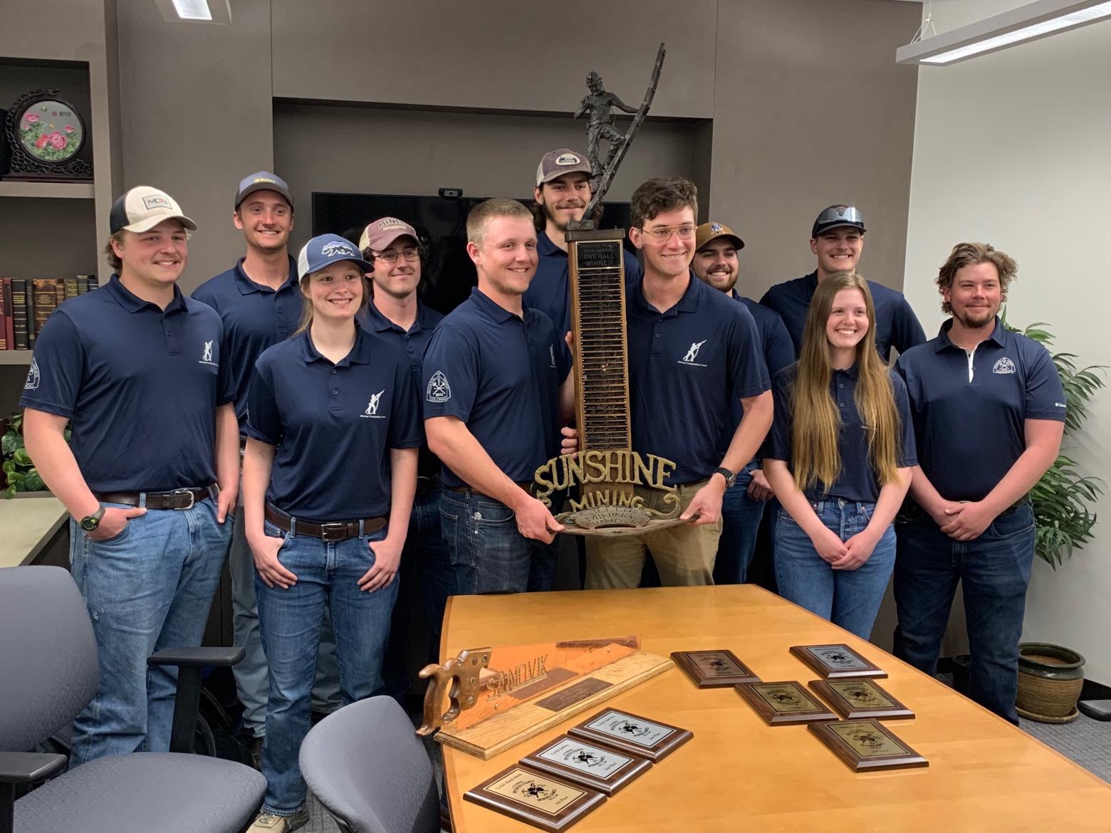 Students in blue Mines polos pose with trophy