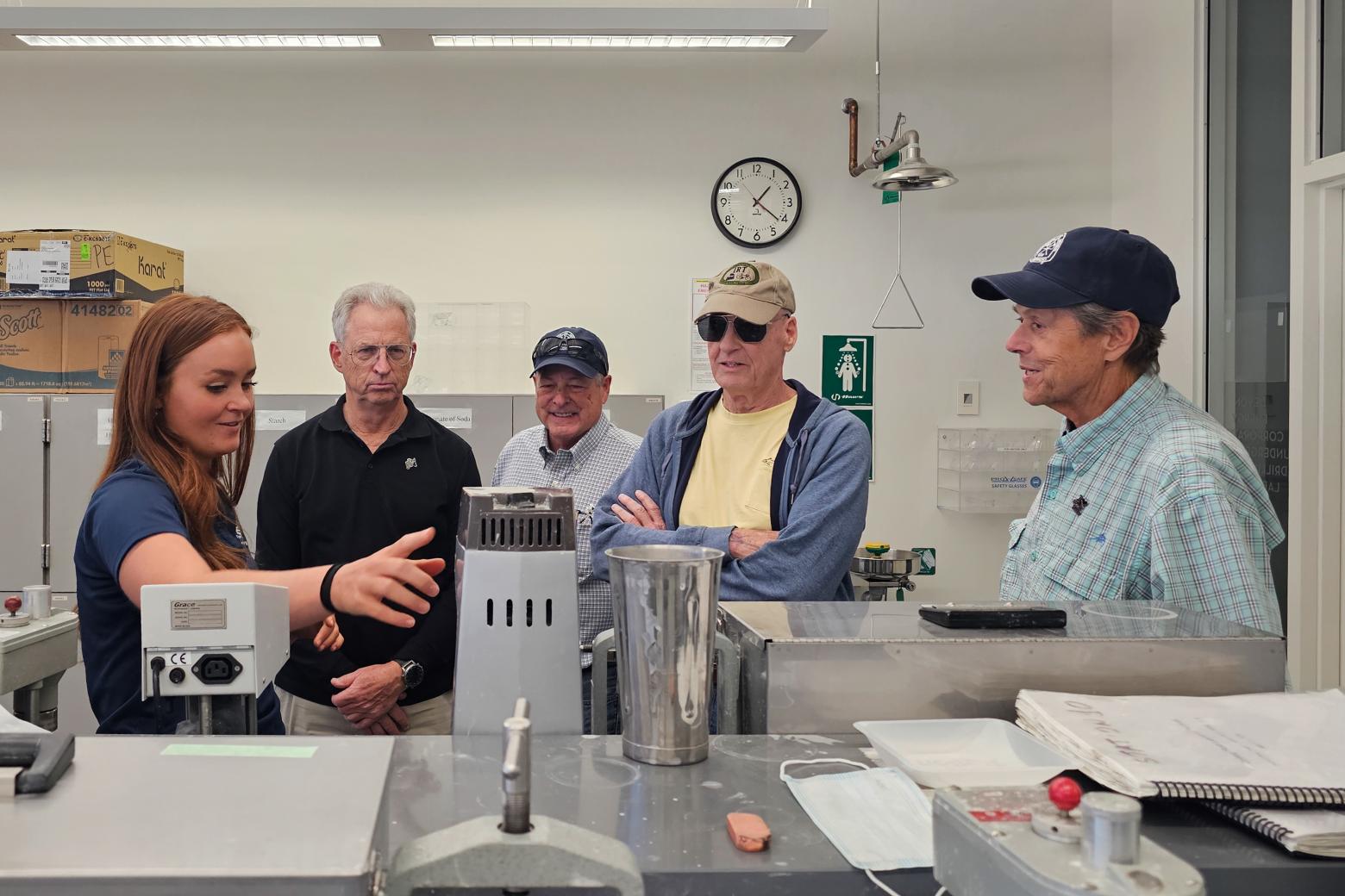 A Mines student shows four Mines alumni around a lab on the Mines campus.