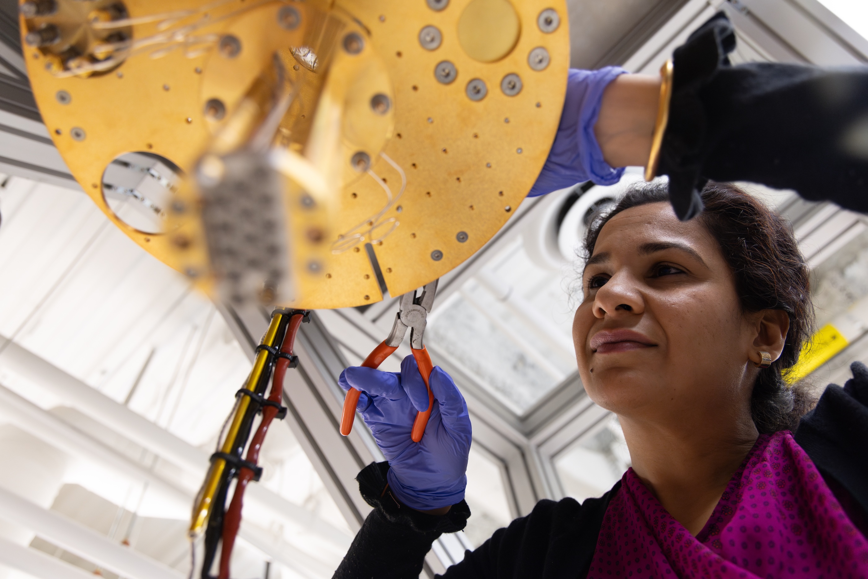 Meenakshi Singh uses pliers on a part of a dilution refrigerator in a quantum lab on the Mines campus.