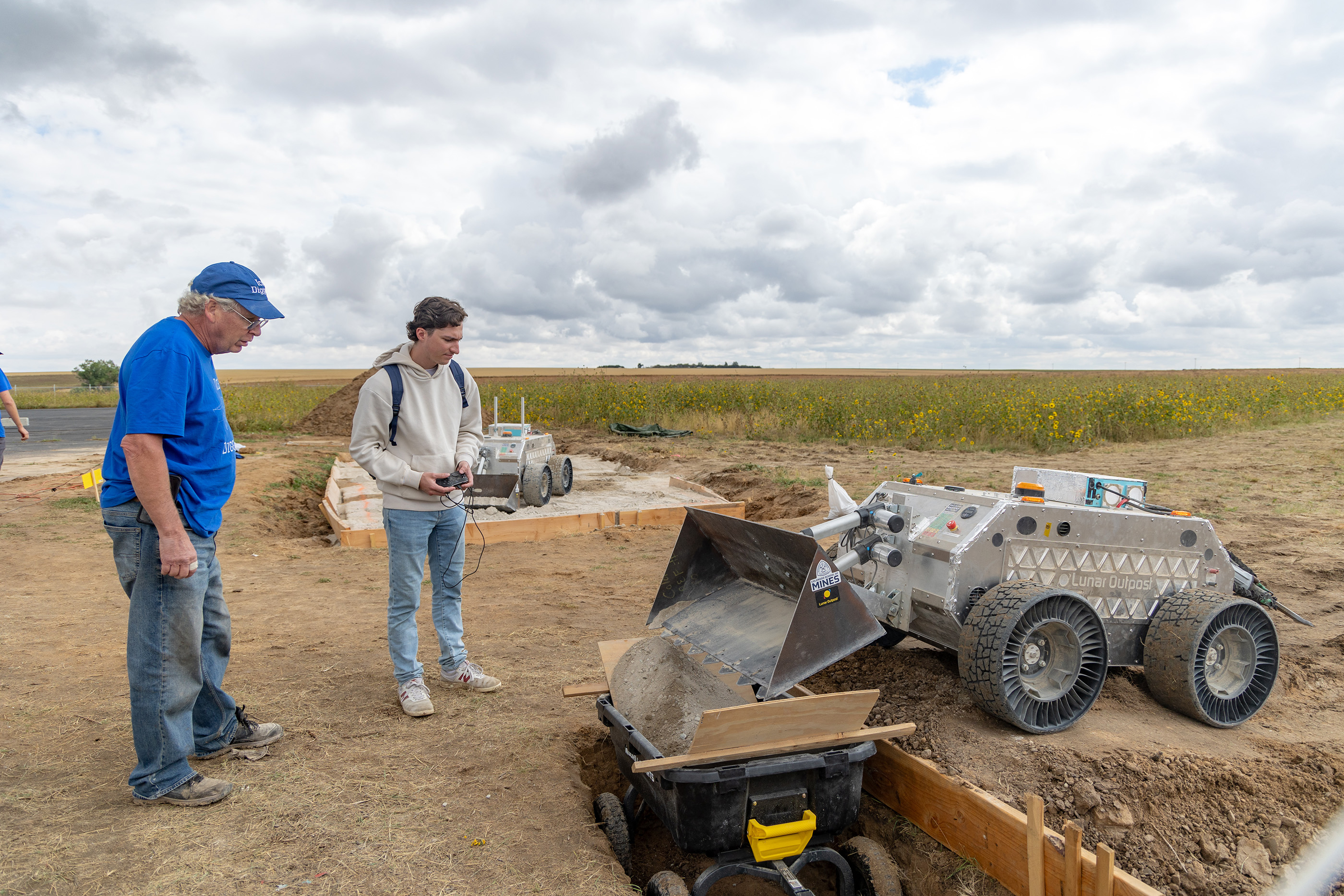 A Mines student with a mentor operates a lunar rover in a field