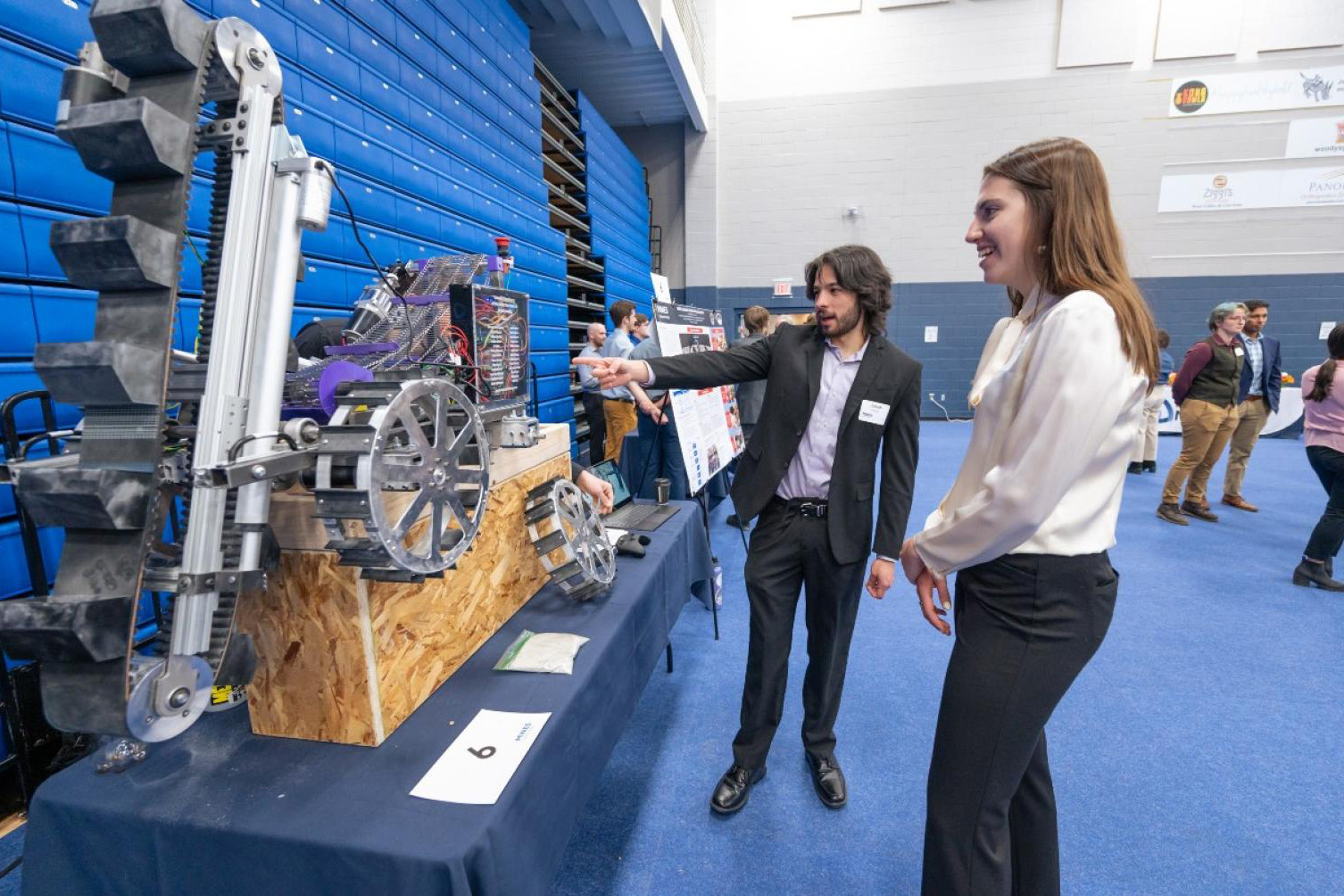 A student shows a Capstone Design attendee a mining robot