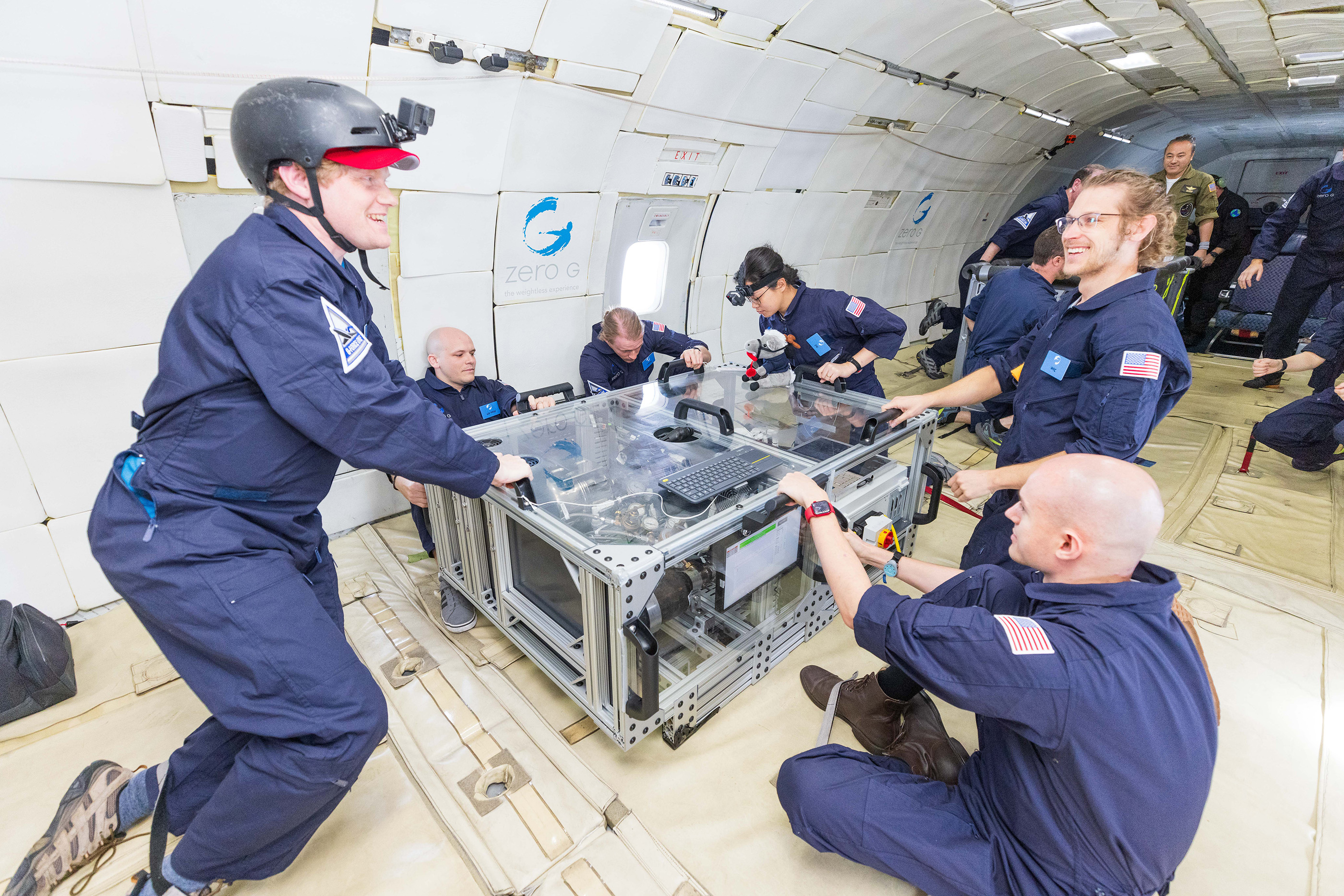 Mines researchers in blue flight suits in a parabolic flight to simulate a low-gravity environment