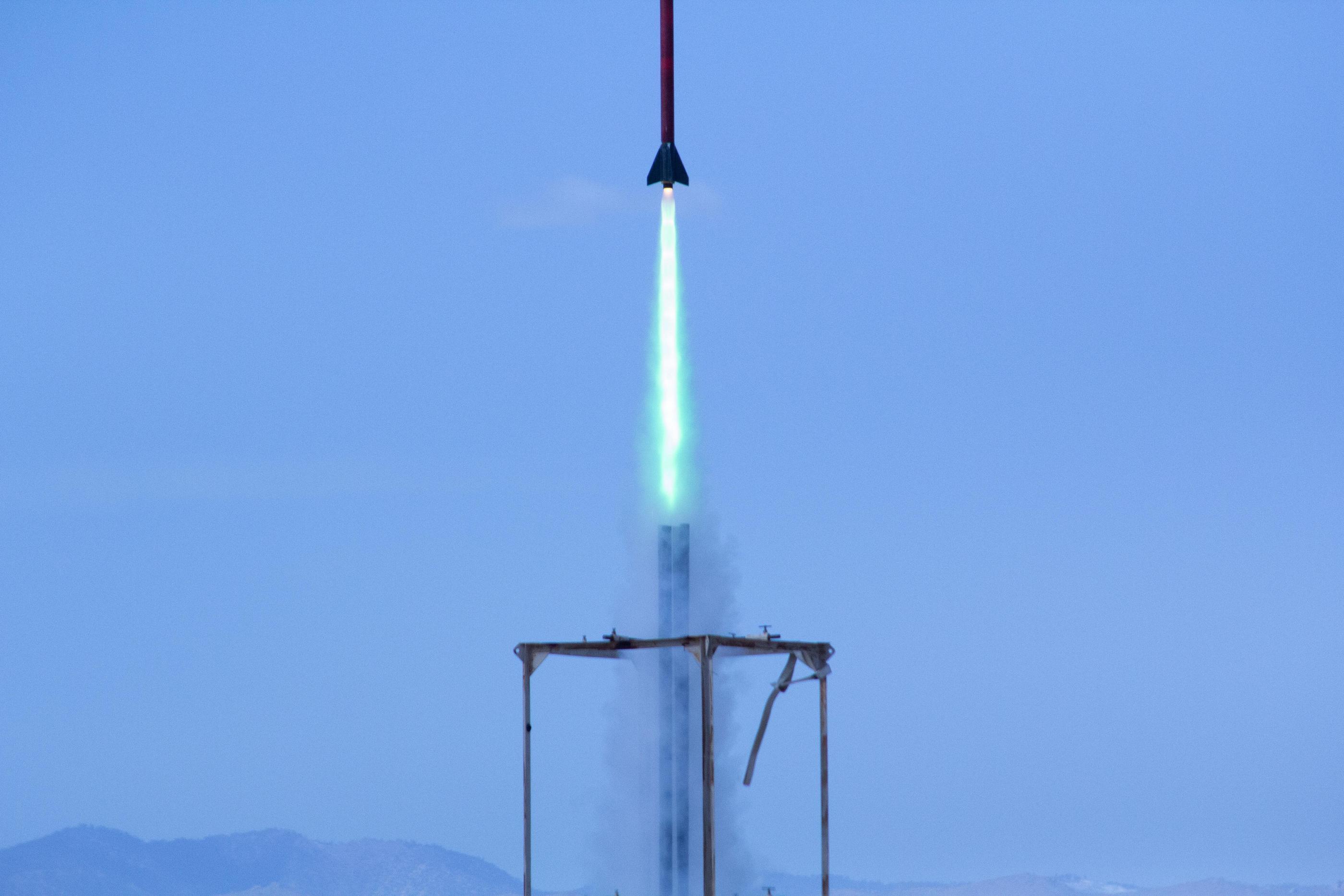 A rocket launching from a platform against a blue sky