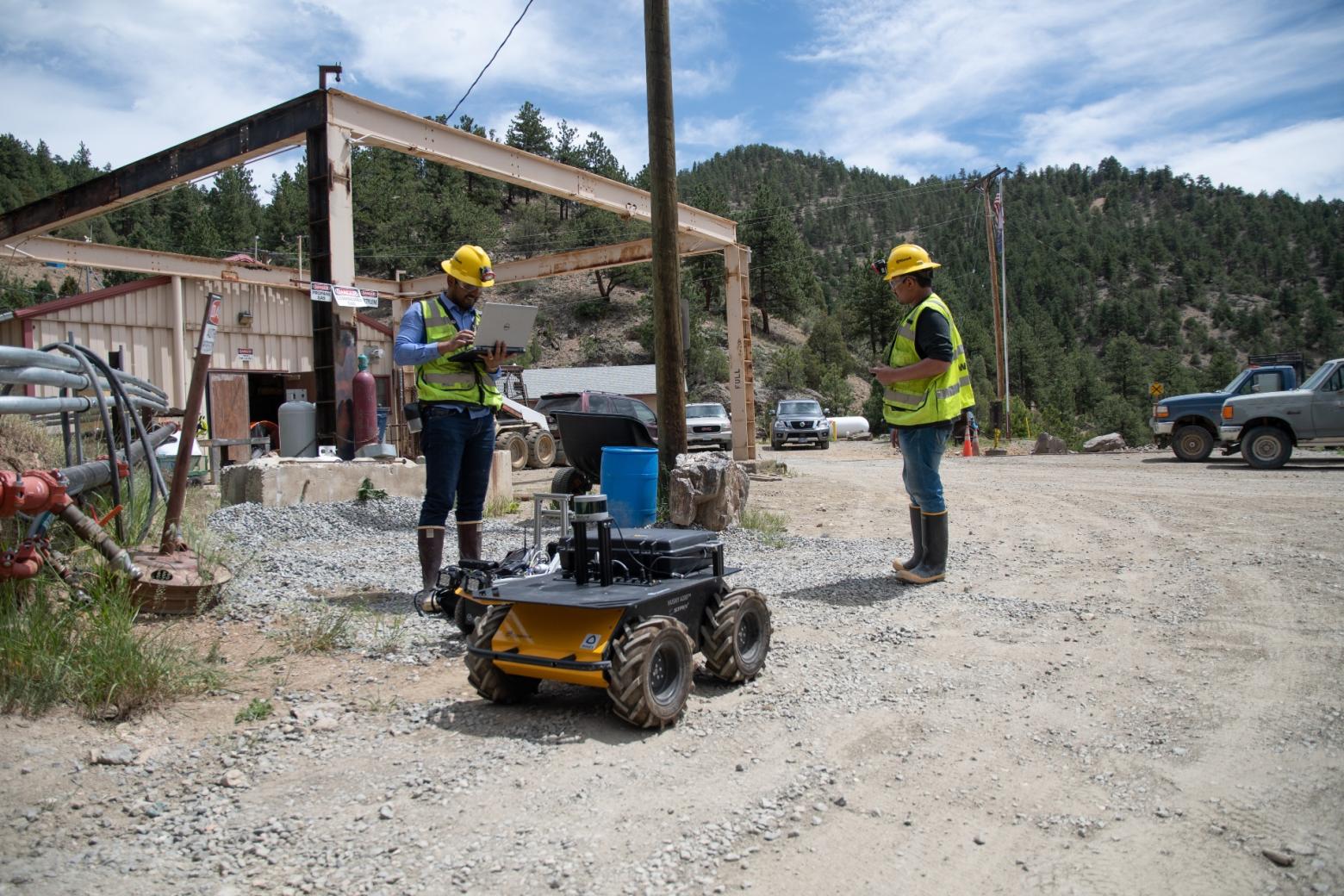 Two Colorado School of Mines team members test operating a four-wheeled robot for mining applications.