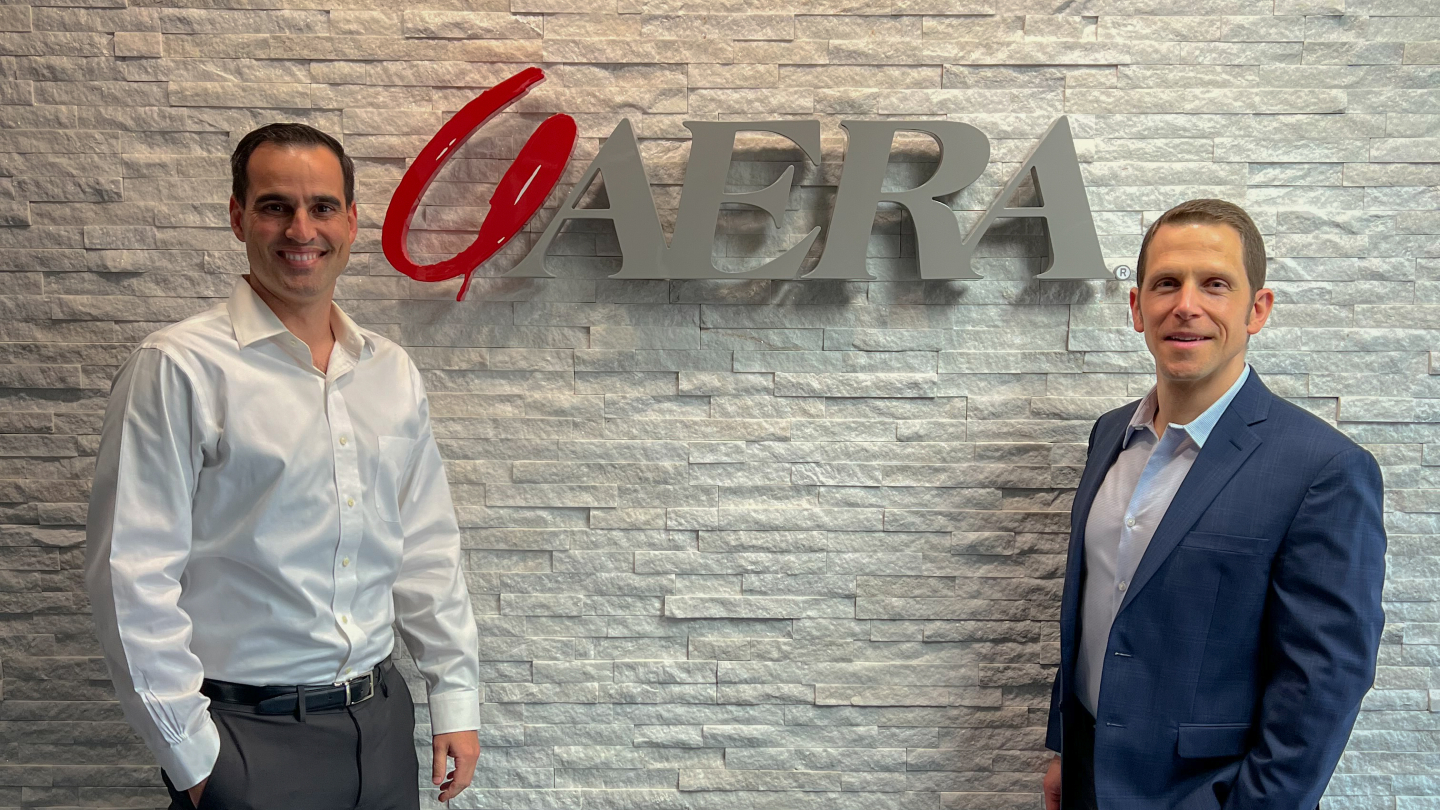 Two Mines alums pose by Aera Energy sign