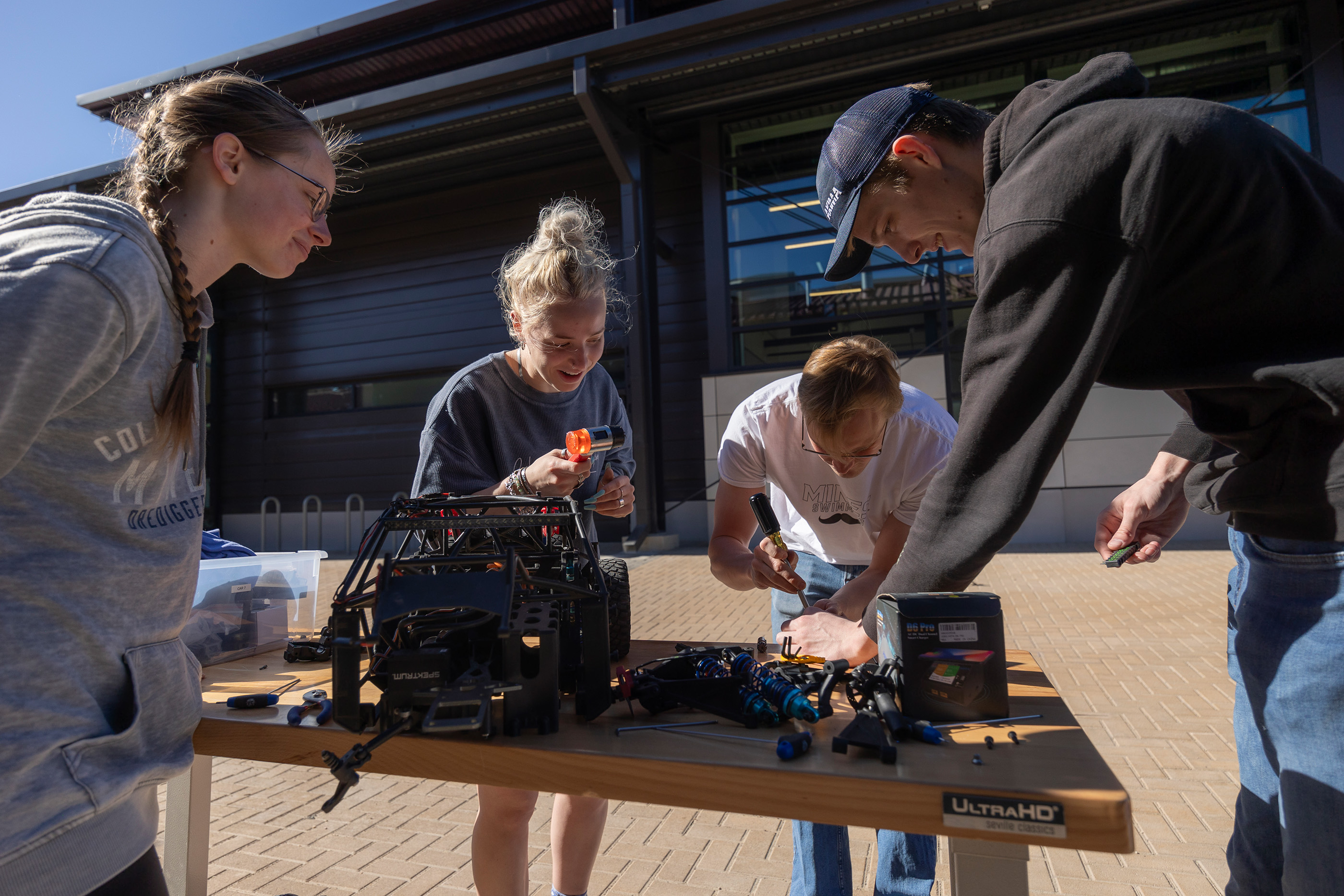 Students work with tools in an outdoor lab space on the Mines campus