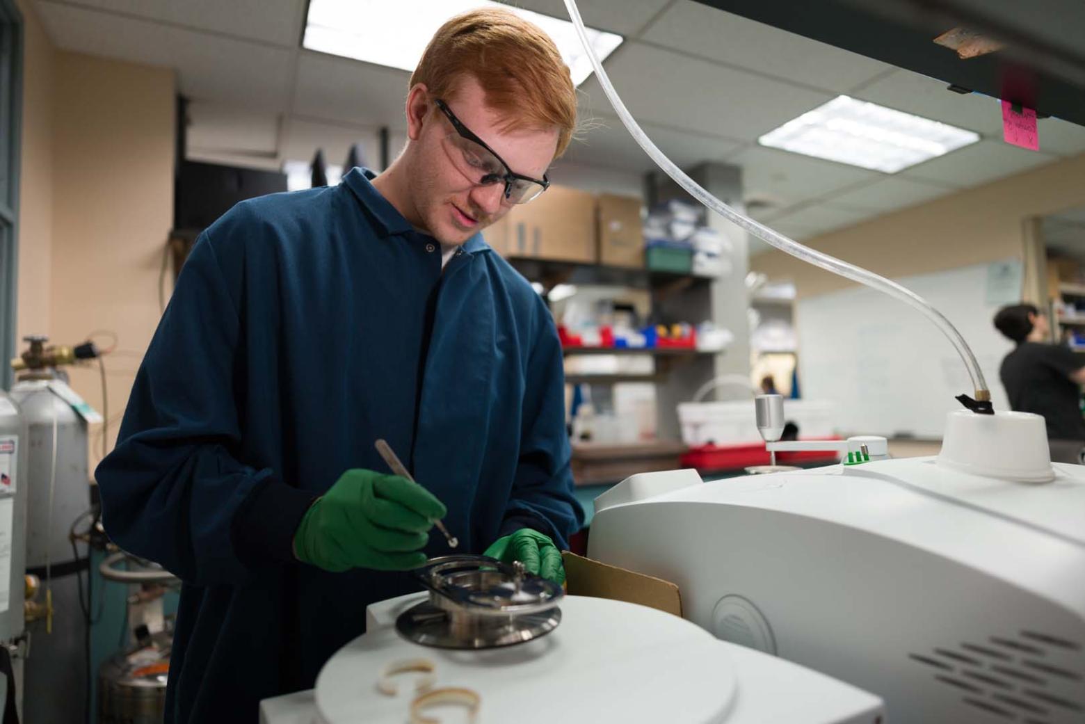 Undergraduate student sets up an experiment in Associate Professor Michael McGuirk’s lab on campus.