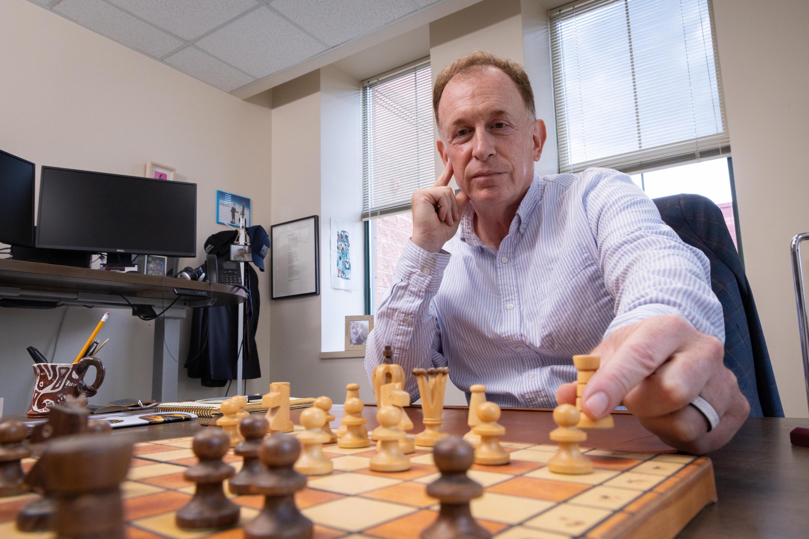 Morgan Bazilian sits at a chess board